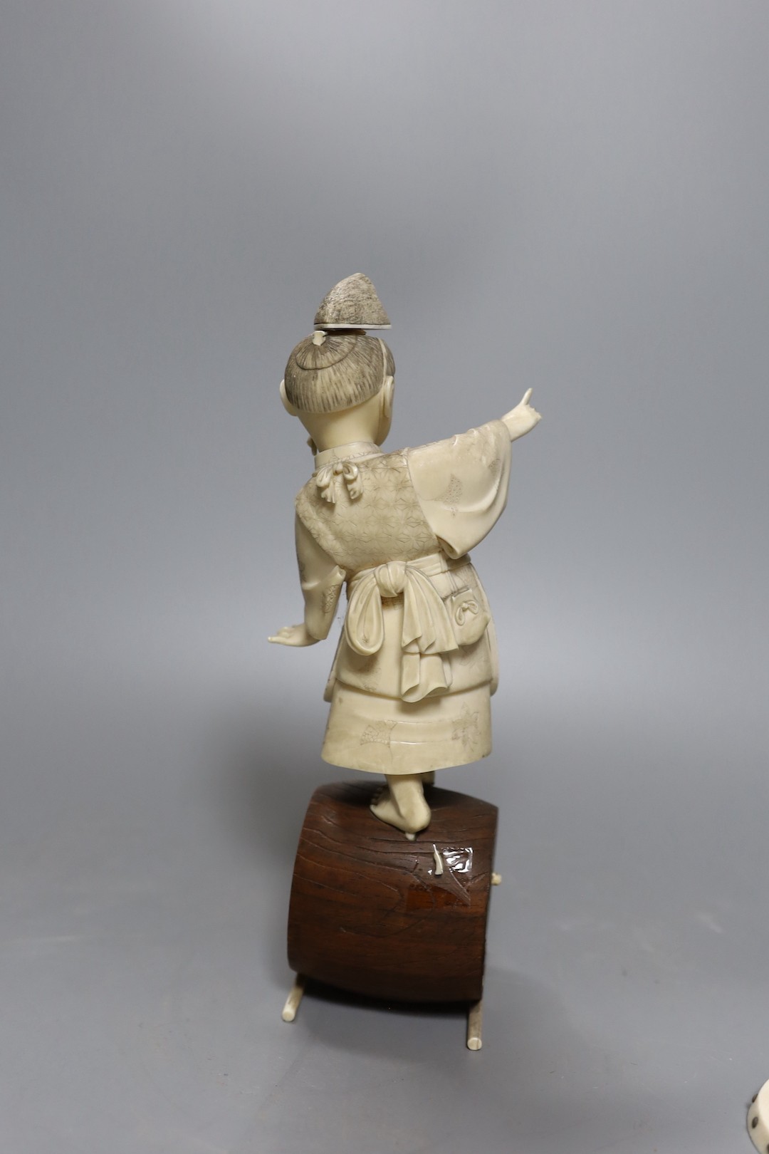 A 19th century Japanese ivory okimono, boy on a barrel with red seal to base, 24cm, together with two carved ivory counters